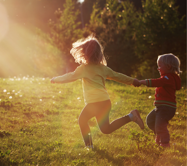 Young children running in an open sun-kissed field.