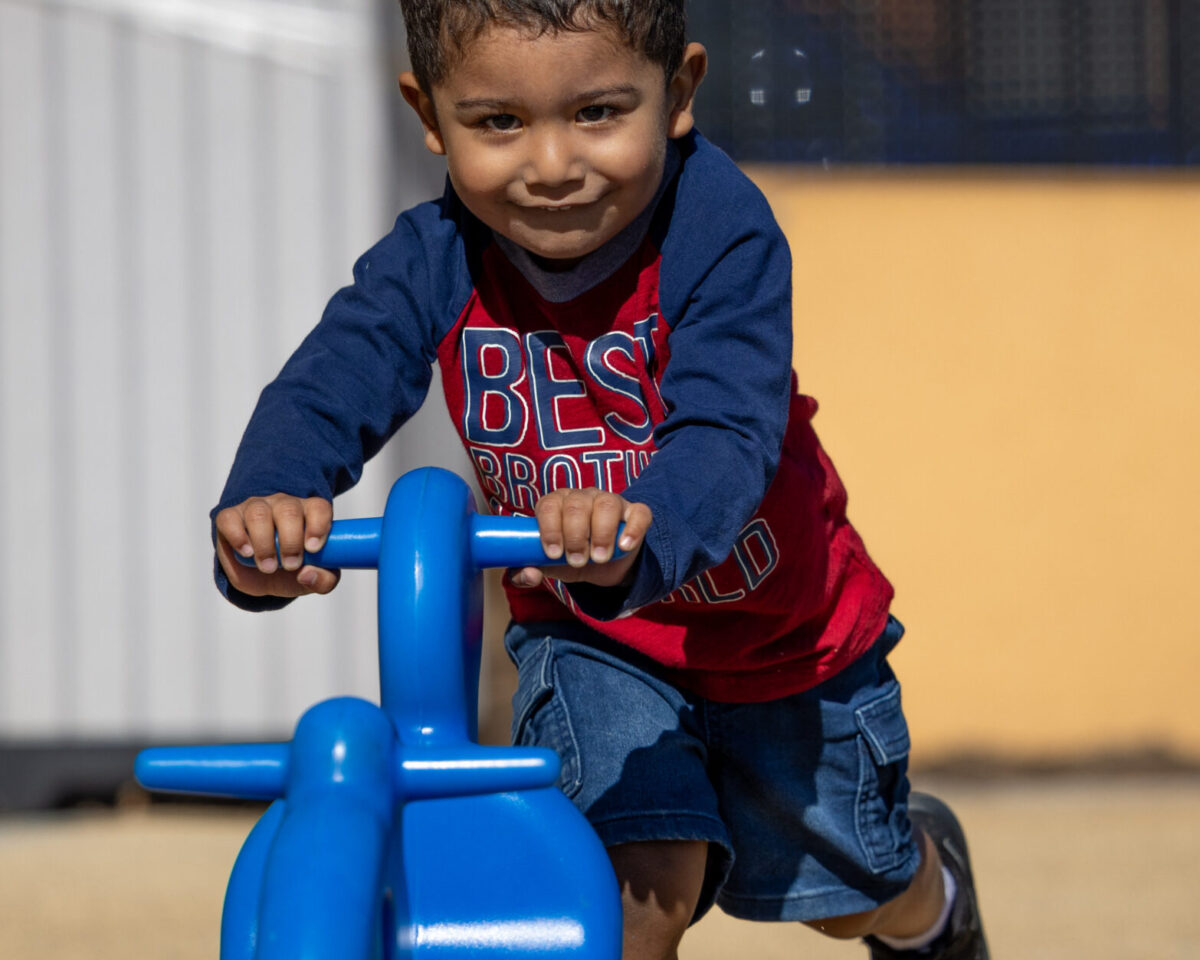 Young boy pushing a blue toy.