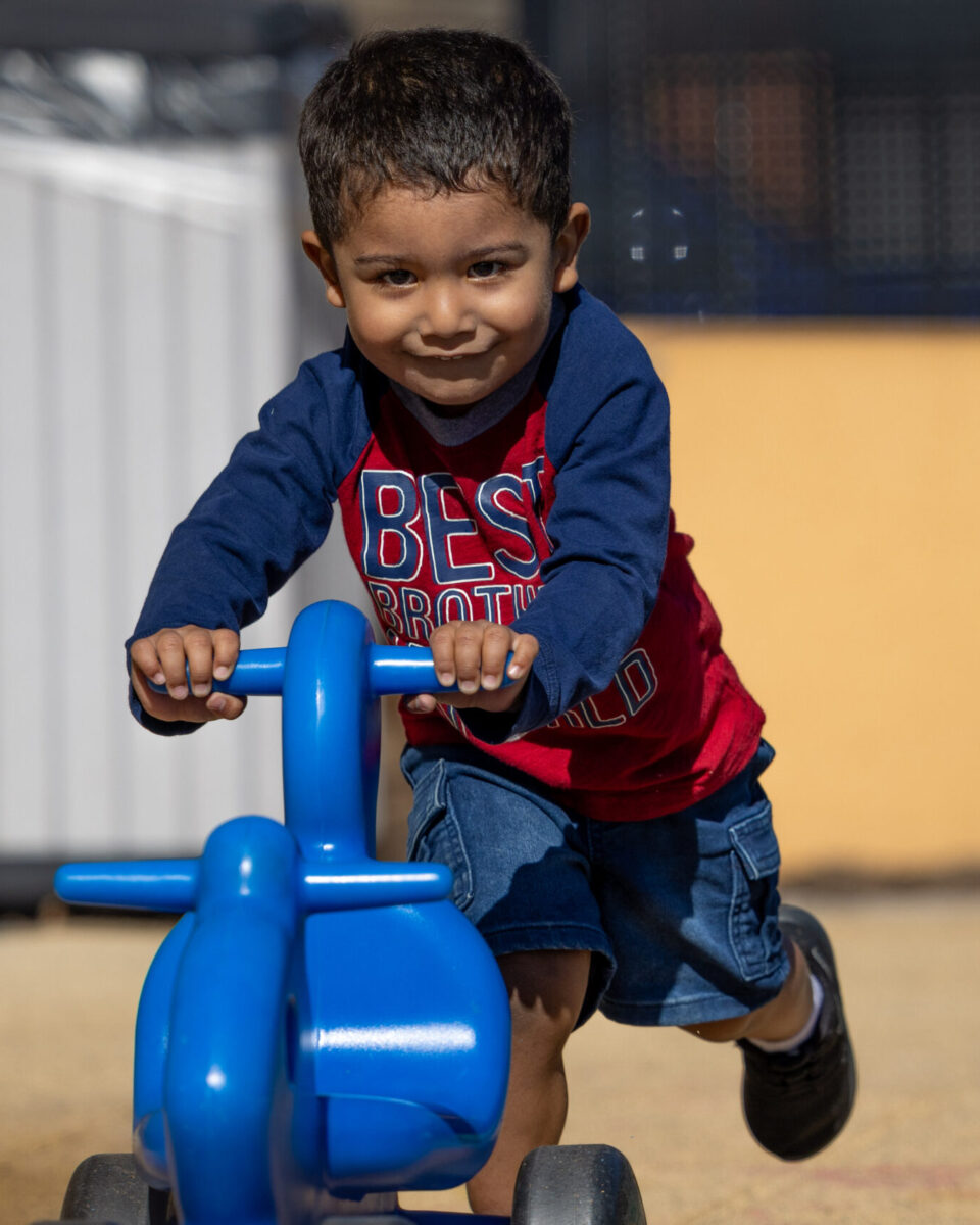 Young boy pushing a blue toy.