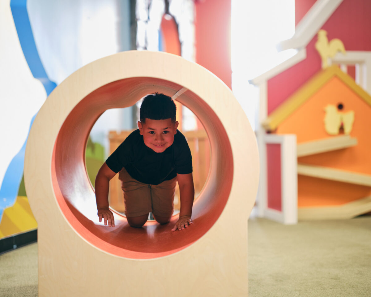 Young boy climbing through a toy at a childcare facility