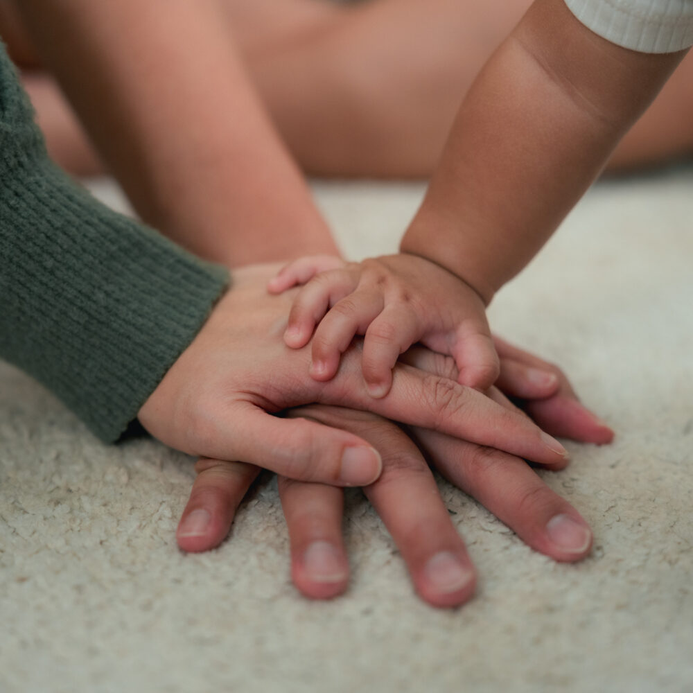 Young parents and child with hands on top of each other 